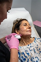 Mystique provider injecting filler in patient's jaw area